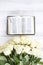 White roses and the Bible on a white wooden background