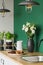 White roses in black and white vase next to coffee jug and big plate with cookies on wooden counter top