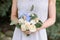 White roses and blue flowers in the bouquet of the bridesmaid.