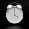 White round analog wall clock isolated on black background, its four oclock