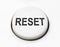 A white round button switch for reset close up.