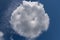 White round cloud, shaped like bun, on blue sky.