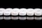 White round pharmaceutical pills on reflective surface, black background