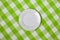 White round plate on green checked tablecloth