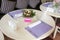 White round table with flower decor, purple napkins and dining appliances. Rose bouquet in elegance cafe interior. Event