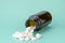 White round tablets scattered in front of glass bottle of pills