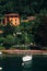 White sailboat anchored near the shore of Varenna, Italy with lush botanical garden in the foreground.