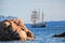 White sailboat with coast of Sardinia island, Costa Esmeralda, Italy