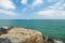 White sailboat on horizon in sea from rocky coast