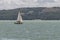 A white sailboat sails on wind-rippled water on Lake Trasimeno near Passignano, Italy