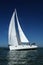 White sailboat taking speed under blue sky