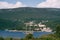 White sailing schooner sails along a blue bay against the backdrop of green mountains and an ancient city