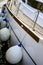 White sailing yacht moored in the port. Protective buoys hanging from the side of the ship. Close-up