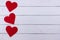 White Saint Valentine`s day background with three red hearts, copy space
