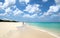 White sand beach walker. Blue sea water and dramatic clouds. Oranjestad, Aruba. Famous Eagle Beach