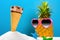White sand with an ice cream cone & starfishes and a pineapple wears sunglasses concept of summer holidays