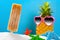 White sand with popsicle and starfishes and a pineapple wears sunglasses concept of summer holidays