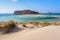 The white sand beside the sea, where the bottom can be seen, the beach with people. Beautiful mountains on a blue horizon.