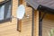 White satellite dish antenna on tha wall of wooden house. Communication and security concept