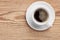 White saucer and cup of coffee with foam on rustic wooden table background top view with space for text