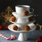 White saucer pyramid with cup of tea on top, like Christmas tree with decorated with sweet chocolate truffles, dark background