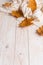 White scarf and dry yellow leaves on a wooden table. Autumn background, copy space