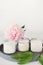 white scented candles on a cement tray and peony flower. soy wax aroma candles in glass unbranded package. home