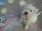 white schnauzer dog sitting in the middle of a rainbow and moon painted with chalks