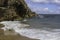 White sea foam on the Mediterranean Sea coast against the backdrop of a textured cliff