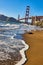 White seafoam around wave on sandy beach with Golden Gate Bridge in background
