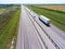 White semi trailer truck driving on wide straight highway in agricultural fields. View from above. The Don M4 route in Russia