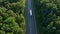 A white semi-truck with an awning trailer crosses the highway located next to the forest. Shooting from the air in the