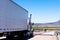 White semi truck and trailer with reflection on the road