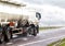 A white semitrailer tractor with a stainless tanker truck transports dangerous goods on the road. Kotsnet transportation