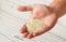 White sesame seeds in man hand, closeup detail, blurred boards table under