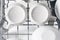 White set of dishes in dishwasher baskets, top view, close-up