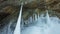 White sharp frozen icicles, stalagmites formed on floor at ice cave in huge rock