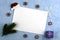 a white sheet on a blue surface, framed by a Santa Claus hat with green fir twigs, gift boxes with lollipops and