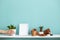 White shelf against pastel turquoise wall with pottery and succulent plant. Hand putting down potted snake plant