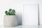 White shelf in the house with a cactus in a pot with a dot pattern and a white frame mockup. Hipster decoration.