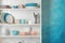 White shelving unit with set of dishware near color wall