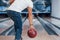 In white shirt and jeans. Rear particle view of man in casual clothes playing bowling in the club