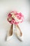 White shoes for a bride stand before pink wedding bouquet