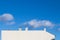 White side of a house and a blue sky with clouds