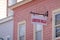 A white sign that says Lobster Rolls in red letters hanging from a house with pink wooden shingles