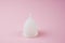 White silicone female menstrual cup on a pink background. No waste. Reusable products. Place for text