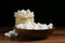 White silk cocoons with bowl and sackcloth bag on wooden table, closeup