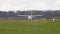 A white single-engine light plane slowly drives across the grass.