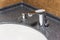 White sink in brown marble countertop with chrome shiny faucet and integrated dispenser for liquid soap