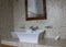 White sink with taps na tiled wall with a mirror